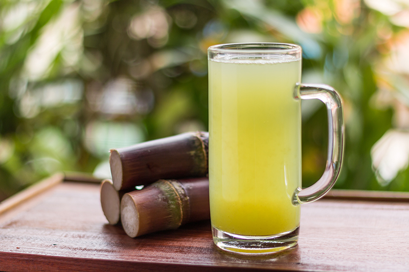 Sugarcane juice with piece of sugarcane on wooden background